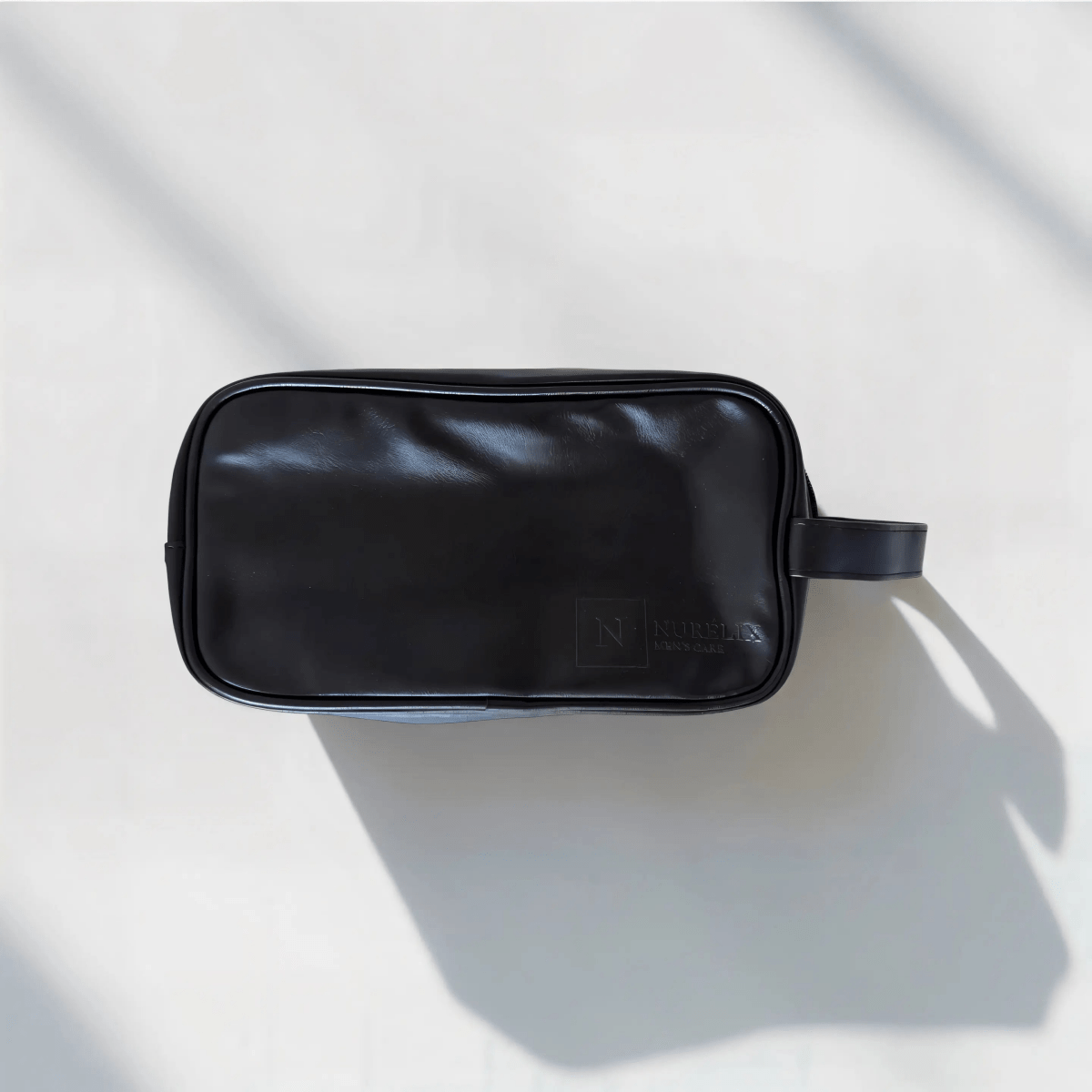 Elegante schwarze Kosmetiktasche aus Kunstleder mit zwei Fächern auf hellem Hintergrund.